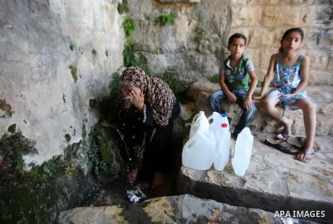 A Palestinian woman fills a jerrican with spring water on June 27, 2016 in Salfit, north of Ramallah, where some of the West Bank village's inhabitants have been without water for days. Tens of thousands of Palestinians...