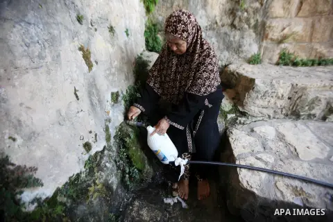 A Palestinian woman fills a jerrican with spring water on June 27, 2016 in Salfit, north of Ramallah, where some of the West Bank village's inhabitants have been without water for days. Tens of thousands of Palestinians...