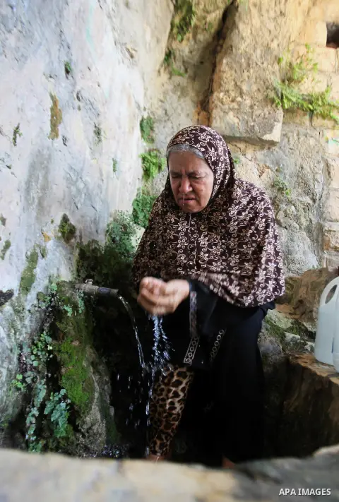 A Palestinian woman fills a jerrican with spring water on June 27, 2016 in Salfit, north of Ramallah, where some of the West Bank village's inhabitants have been without water for days. Tens of thousands of Palestinians...
