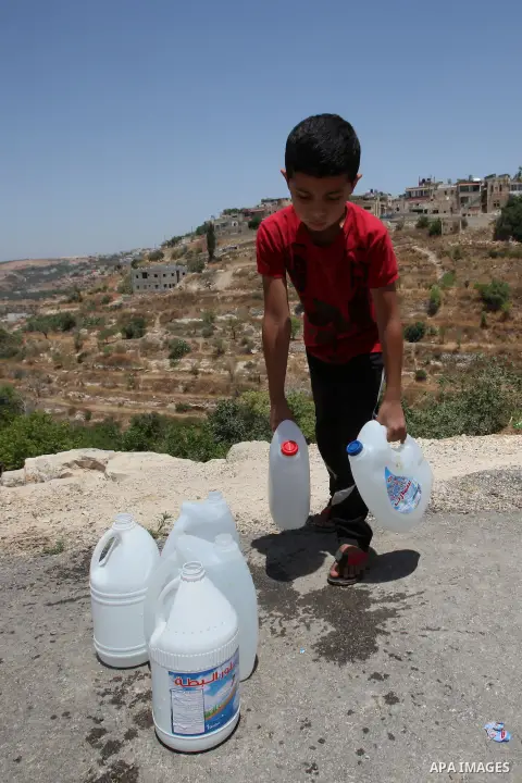 A Palestinian boy carries a jerrican filled with spring water on June 27, 2016 in Salfit, north of Ramallah, where some of the West Bank village's inhabitants have been without water for days. Tens of thousands of Palest...
