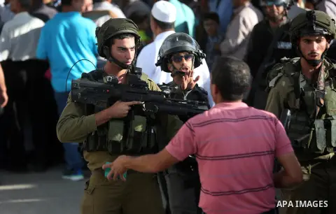 Palestinians wait to cross through Israeli Qalandia checkpoint as they make their way to attend the last Friday prayer of the holy fasting month of Ramadan in Jerusalem's al-Aqsa mosque, near the West Bank city of Ramall...