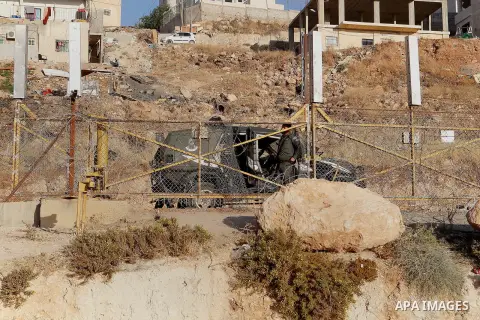 Palestinians run for a cover from teargas canisters fired by Israeli border police near a barbed-wire gate part of the controversial Israeli separation fence between the West Bank town of Bethlehem and Jerusalem, after a...