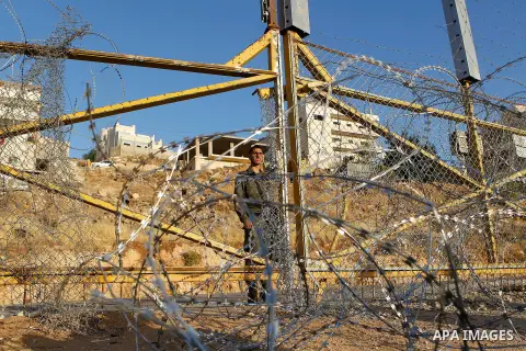 An Israeli border policeman stands guard near a gap in the barbed-wire gate part of the controversial Israeli separation fence between the West Bank town of Bethlehem and Jerusalem, after an attempt by Palestinian men to...