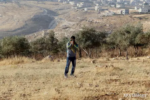 Palestinians run for a cover from teargas canisters fired by Israeli border police near a barbed-wire gate part of the controversial Israeli separation fence between the West Bank town of Bethlehem and Jerusalem, after a...