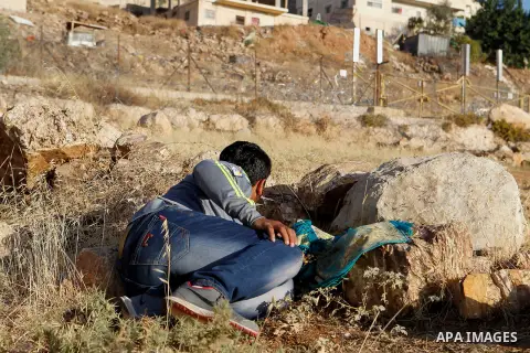 Palestinians run for a cover from teargas canisters fired by Israeli border police near a barbed-wire gate part of the controversial Israeli separation fence between the West Bank town of Bethlehem and Jerusalem, after a...
