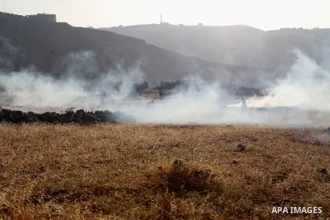 Palestinians run for a cover from teargas canisters fired by Israeli border police near a barbed-wire gate part of the controversial Israeli separation fence between the West Bank town of Bethlehem and Jerusalem, after a...