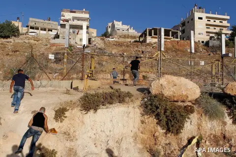 Palestinian men cross through a gap in the barbed-wire gate part of the controversial Israeli separation fence between the West Bank town of Bethlehem and Jerusalem, in an attempt to reach the Al-Aqsa Mosque compound in...