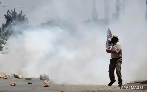 A Palestinian protester runs for cover from a tear gas fired by Israeli security forces during clashes following a demonstration against the expropriation of Palestinian land by Israel on July 01, 2016 in the village of...