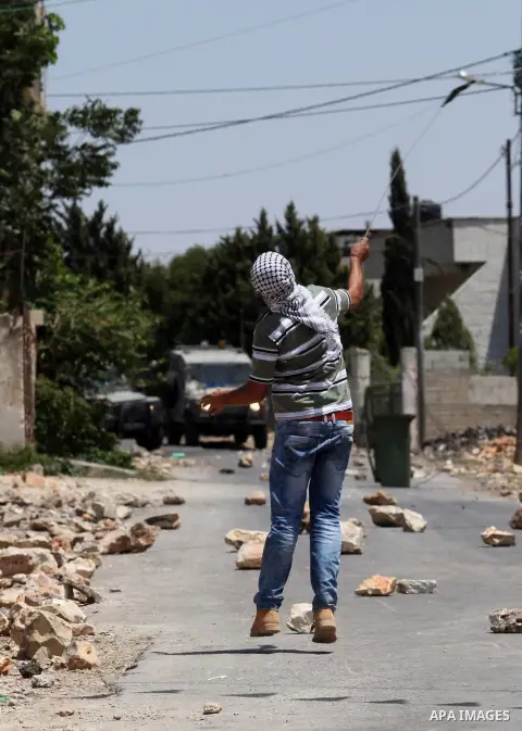 A Palestinian protester uses a slingshot to hurl stones towards Israeli security forces during clashes following a demonstration against the expropriation of Palestinian land by Israel on July 01, 2016 in the village of...