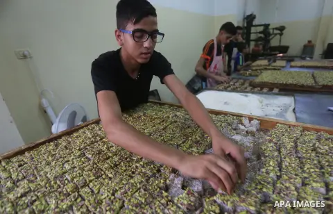 Palestinians prepare sweet known in Arabic as "Halkoum" ahead of the Eid al-Fitr holiday, in Gaza city, on July 3, 2016. Eid al-Fitr marks the end of Muslim's holy fasting month of Ramadan when faithfuls abstain from eat...
