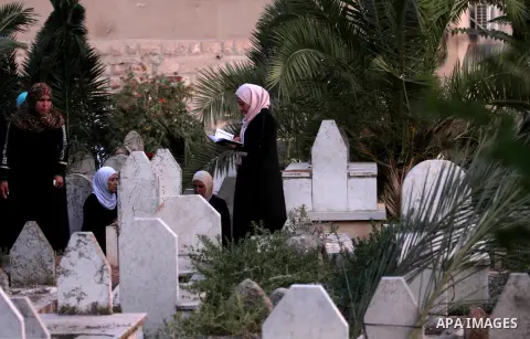 Palestinian women visit the graves of relatives at a cemetery on the first day of Eid al-Fitr celebrations, which marks the end of the holy fasting month of Ramadan, in the West Bank city of Nablus, on July 6, 2016. Phot...