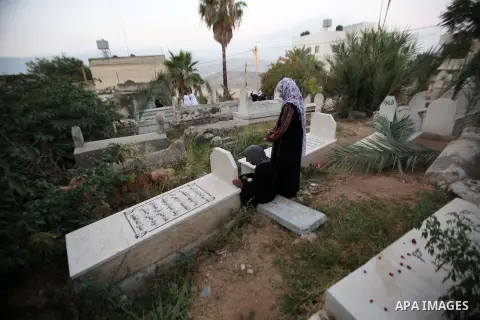 Palestinian women visit the graves of relatives at a cemetery on the first day of Eid al-Fitr celebrations, which marks the end of the holy fasting month of Ramadan, in the West Bank city of Nablus, on July 6, 2016. Phot...
