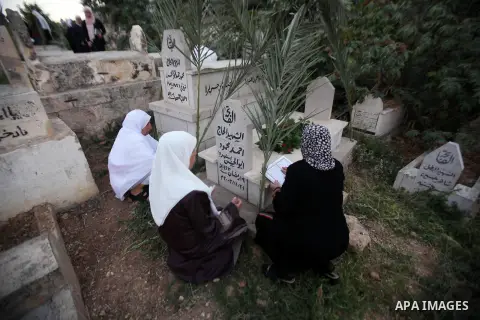 Palestinian women visit the graves of relatives at a cemetery on the first day of Eid al-Fitr celebrations, which marks the end of the holy fasting month of Ramadan, in the West Bank city of Nablus, on July 6, 2016. Phot...