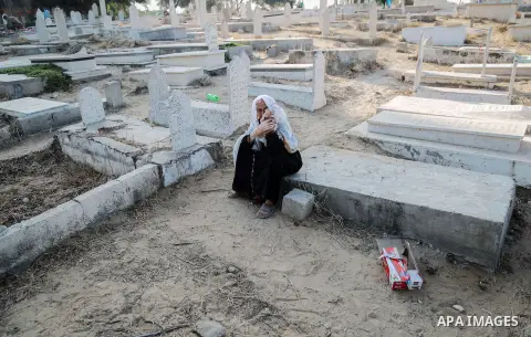 A Palestinian woman visits the grave of her relative at a cemetery on the first day of Eid al-Fitr celebrations, which marks the end of the holy fasting month of Ramadan, in Gaza City July 6, 2016. Photo by Mohammed Dahm...