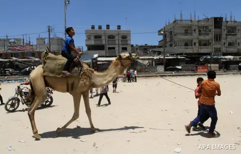 Palestinian children enjoy riding a camel to celebrate Eid al-Fitr during the second day of the holiday of Eid al-Fitr marking the end of Islam's fasting holy month of Ramadan, in Rafah in the southern Gaza strip, on Jul...