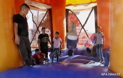 Palestinian children play to celebrate Eid al-Fitr during the second day of the holiday of Eid al-Fitr marking the end of Islam's fasting holy month of Ramadan, in the West Bank city of Hebron, on July 7, 2016. Photo by...