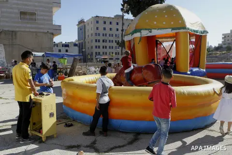 Palestinian children play to celebrate Eid al-Fitr during the second day of the holiday of Eid al-Fitr marking the end of Islam's fasting holy month of Ramadan, in the West Bank city of Hebron, on July 7, 2016. Photo by...