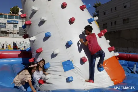 Palestinian children play to celebrate Eid al-Fitr during the second day of the holiday of Eid al-Fitr marking the end of Islam's fasting holy month of Ramadan, in the West Bank city of Hebron, on July 7, 2016. Photo by...