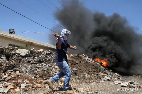 A Palestinian protester uses a slingshot to hurl stones towards Israeli security forces during clashes following a demonstration against the expropriation of Palestinian land by Israel on July 08, 2016 in the village of...