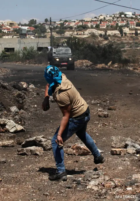A Palestinian protester uses a slingshot to hurl stones towards Israeli security forces during clashes following a demonstration against the expropriation of Palestinian land by Israel on July 08, 2016 in the village of...
