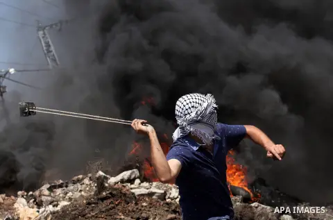 A Palestinian protester uses a slingshot to hurl stones towards Israeli security forces during clashes following a demonstration against the expropriation of Palestinian land by Israel on July 08, 2016 in the village of...