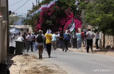 Palestinian protesters run for cover from tear gas fired by Israeli security forces during clashes following a demonstration against the expropriation of Palestinian land by Israel on July 08, 2016 in the village of Kfar...