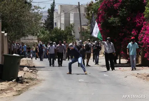A Palestinian protester uses a slingshot to hurl stones towards Israeli security forces during clashes following a demonstration against the expropriation of Palestinian land by Israel on July 08, 2016 in the village of...