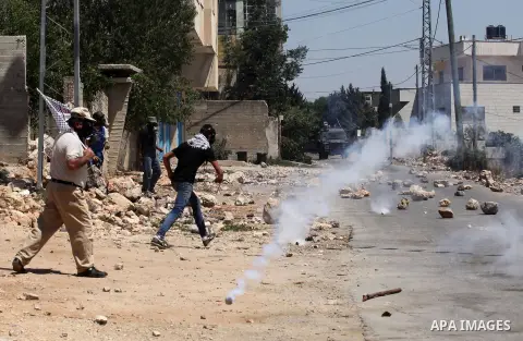 Palestinian protesters run for cover from a tear gas canister fired by Israeli security forces during clashes following a demonstration against the expropriation of Palestinian land by Israel on July 15, 2016 in the vill...