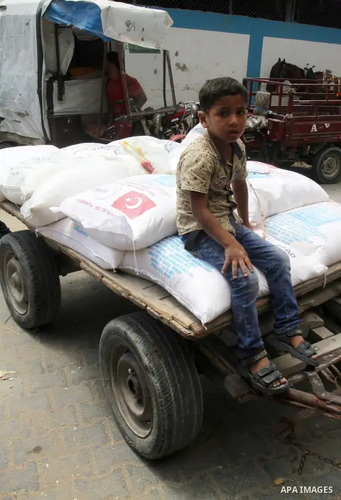 Palestinians receive Turkish aid at an aid distribution centre of the United Nations Relief and Works Agency (UNRWA) in the southern Gaza Strip town of Rafah, on July 18, 2016. Photo by Abed Rahim Khatib