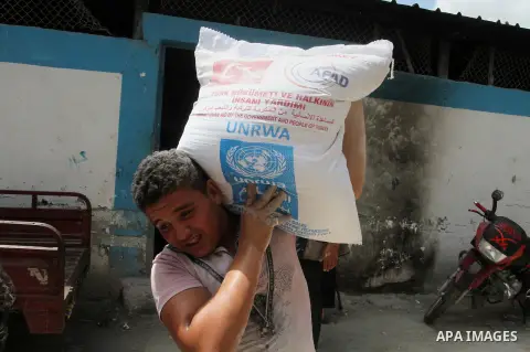 Palestinians receive Turkish aid at an aid distribution centre of the United Nations Relief and Works Agency (UNRWA) in the southern Gaza Strip town of Rafah, on July 18, 2016. Photo by Abed Rahim Khatib
