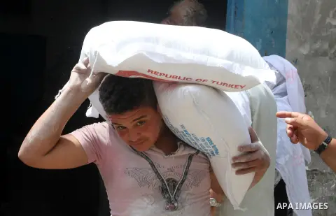 Palestinians receive Turkish aid at an aid distribution centre of the United Nations Relief and Works Agency (UNRWA) in the southern Gaza Strip town of Rafah, on July 18, 2016. Photo by Abed Rahim Khatib