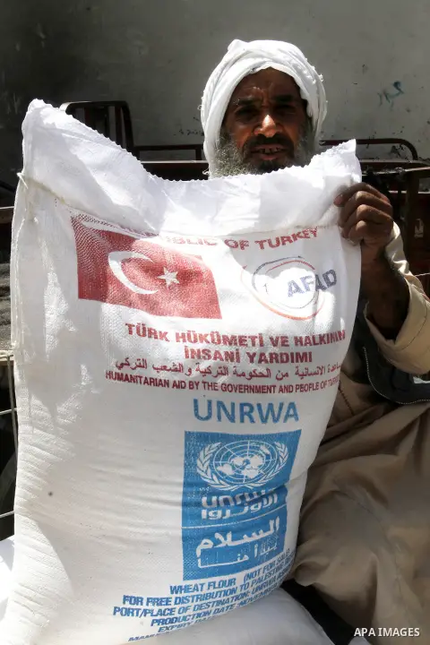 Palestinians receive Turkish aid at an aid distribution centre of the United Nations Relief and Works Agency (UNRWA) in the southern Gaza Strip town of Rafah, on July 18, 2016. Photo by Abed Rahim Khatib