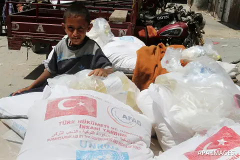Palestinians receive Turkish aid at an aid distribution centre of the United Nations Relief and Works Agency (UNRWA) in the southern Gaza Strip town of Rafah, on July 18, 2016. Photo by Abed Rahim Khatib
