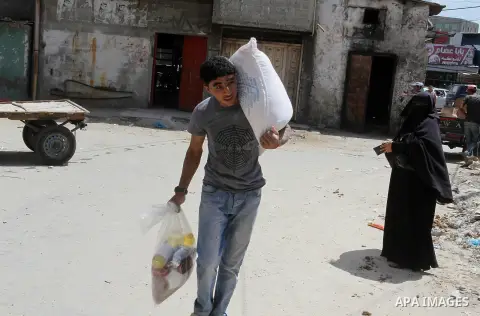 Palestinians receive Turkish aid at an aid distribution centre of the United Nations Relief and Works Agency (UNRWA) in the southern Gaza Strip town of Rafah, on July 18, 2016. Photo by Abed Rahim Khatib