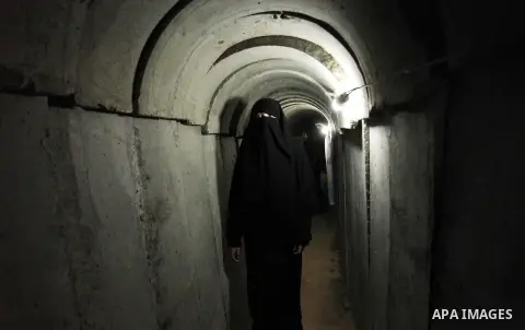 A Palestinian woman walks inside a tunnel used for military exercises during a weapon exhibition at a Hamas-run youth summer camp, in Gaza City, on July 21, 2016. Photo by Ashraf Amra