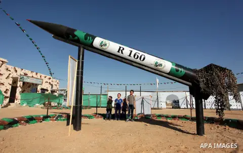 Palestinians walk next to a rocket during a weapon exhibition at a Hamas-run youth summer camp, in Gaza City, on July 21, 2016. Photo by Ashraf Amra