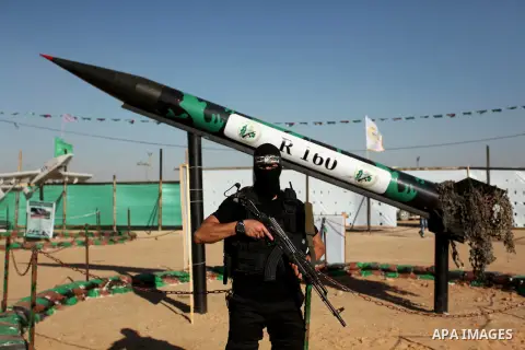 A member of the Ezzedine al-Qassam Brigades, the military wing of the Palestinian Islamist movement Hamas stands in front of a rocket during a weapon exhibition at a Hamas-run youth summer camp, in Gaza City, on July 21,...