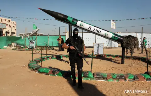 A member of the Ezzedine al-Qassam Brigades, the military wing of the Palestinian Islamist movement Hamas stands in front of a rocket during a weapon exhibition at a Hamas-run youth summer camp, in Gaza City, on July 21,...
