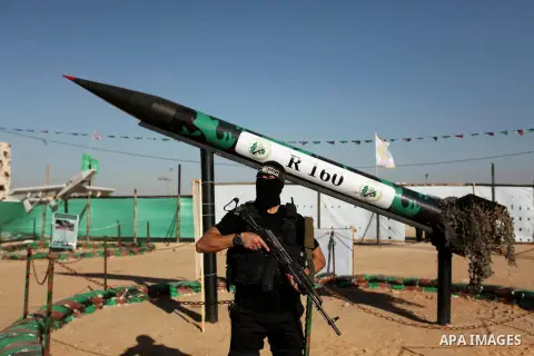 A member of the Ezzedine al-Qassam Brigades, the military wing of the Palestinian Islamist movement Hamas stands in front of a rocket during a weapon exhibition at a Hamas-run youth summer camp, in Gaza City, on July 21,...