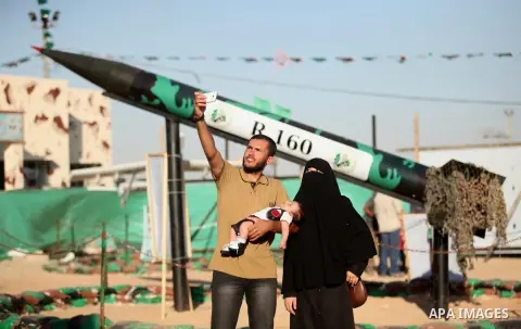Palestinians take selfie next to a rocket during a weapon exhibition at a Hamas-run youth summer camp, in Gaza City, on July 21, 2016. Photo by Ashraf Amra
