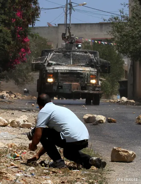 A Palestinian protester collects stones to throw towards Israeli security forces during clashes following the weekly demonstration against the expropriation of Palestinian land by Israel in the village of Kfar Qaddum, ne...