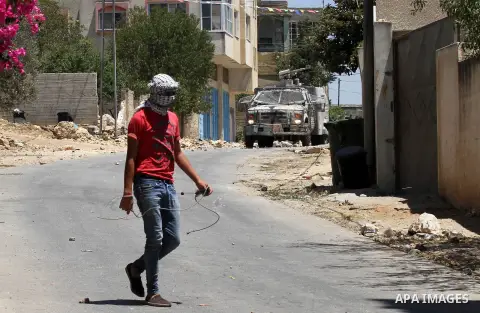 A Palestinian protester uses a slingshot to hurl stones towards Israeli security forces during clashes following the weekly demonstration against the expropriation of Palestinian land by Israel in the village of Kfar Qad...