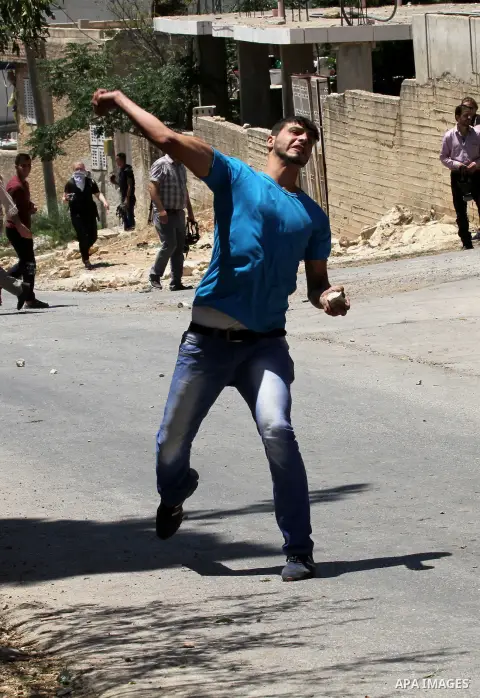 A Palestinian protester throws stones towards Israeli security forces during clashes following the weekly demonstration against the expropriation of Palestinian land by Israel in the village of Kfar Qaddum, near Nablus,...