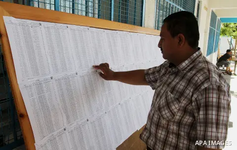 Palestinians look for their names on the registered voters' list at Voter registration centers in Rafah in the southern Gaza strip on July 23, 2016. The Palestinian Central Elections Commission (CEO) announced Saturday t...