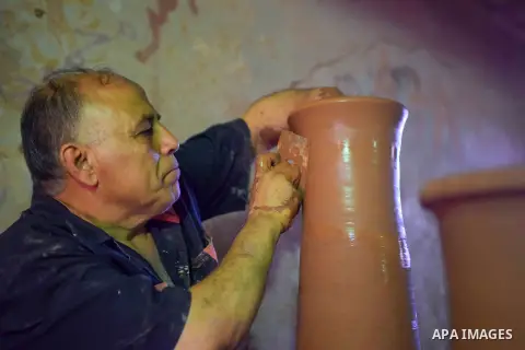 An Egyptian man uses a pottery wheel to construct a clay vessel, at a pottery workshop in Cairo, on July 24, 2016. Pottery is an ancient and traditional craft in Egypt. Local workshops usually produce products such as bo...