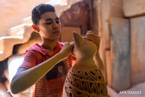 An Egyptian boy works at a pottery workshop in Cairo, on July 24, 2016. Pottery is an ancient and traditional craft in Egypt. Local workshops usually produce products such as bowls, pitchers, flower pots, and vases. Phot...