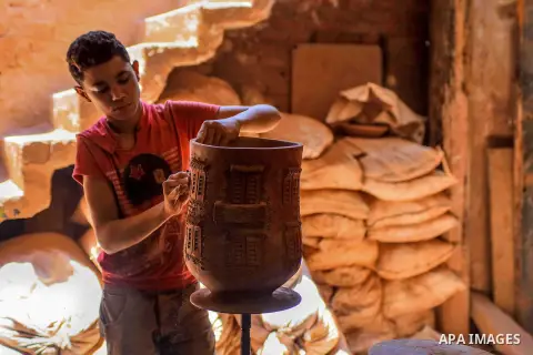 An Egyptian boy works at a pottery workshop in Cairo, on July 24, 2016. Pottery is an ancient and traditional craft in Egypt. Local workshops usually produce products such as bowls, pitchers, flower pots, and vases. Phot...