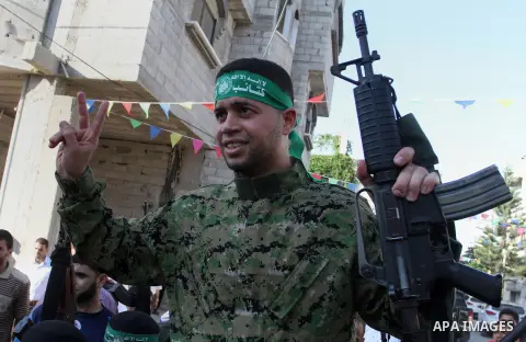 Freed Palestinian prisoner Mohammed al-Bashiti, who served 12 years in an Israeli jail after he was convicted of being a member of Hamas's armed wing, waves as he sits on the shoulders of a Hamas militant upon his releas...