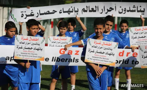 Palestinian boys hold placards demanding for end the siege during a training season for football school at Al Jazeera club in Gaza city, on July 26, 2016. Photo by Mohammed Asad