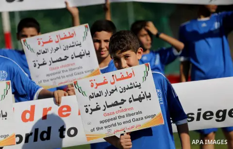 Palestinian boys hold placards demanding for end the siege during a training season for football school at Al Jazeera club in Gaza city, on July 26, 2016. Photo by Mohammed Asad